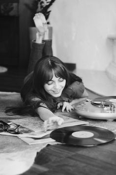 a woman laying on the floor next to an old record player and playing with her hands