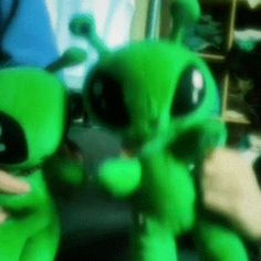 a green alien stuffed animal sitting on top of a table