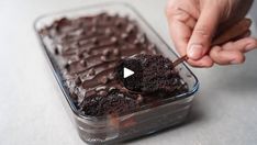 a person holding a spoon over a chocolate cake