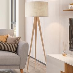 a living room with a gray couch and wooden floor lamp next to a white wall