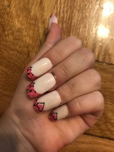 a woman's hand with white and pink nail polishes on her nails, which are decorated with hearts