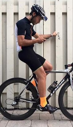 a man sitting on top of a bike next to a white fence and wearing yellow socks