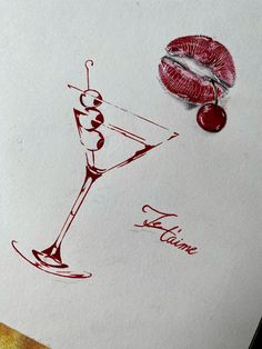 a drawing of a martini glass with a cherry on the rim next to it and a red lip