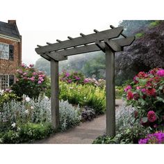 a garden with lots of flowers and plants around it, including an arbor in the middle