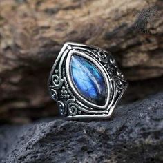 a silver ring with a blue stone in the middle on top of a rocky surface