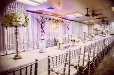 a long banquet table with white flowers and candles on the tables is set up for an event