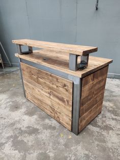 a wooden counter sitting on top of a cement floor next to a gray and white wall