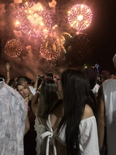 people standing around watching fireworks in the sky