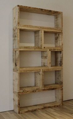 a wooden shelf with several shelves on the top and bottom, in front of a white wall