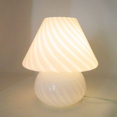 a white lamp sitting on top of a table next to a light bulb in the shape of a cone