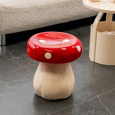 a red mushroom stool sitting on top of a black floor next to a white bed