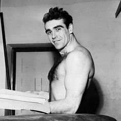 black and white photograph of a shirtless man holding a book