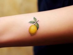 a small yellow lemon tattoo on the arm