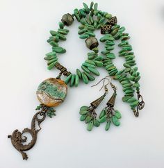 "This yummy new necklace is designed with my handmade lampwork glass bead in warm caramel brown and green, wire wrapped with a Vintaj antique brass sea serpent and jade green Swarovski crystals. The body of the necklace is genuine turquoise gemstones, antique brass, and 2 more lampwork beads. The clasp is an S hook and loop. You'll fall in love with this one of a kind lampwork and turquoise necklace! The necklace measures 20 1/2\" with a 3 3/4\" long pendant and the coordinating earrings measure Turquoise Czech Glass Jewelry With Natural Stones, Handmade Turquoise Necklace In Czech Glass, Green Wire Wrapped Czech Glass Necklace, Artisan Wire Wrapped Czech Glass Necklaces, Artisan Czech Glass Wire Wrapped Necklaces, Artisan Wire Wrapped Necklace For Jewelry Making, Artisan Wire Wrapped Czech Glass Necklace, Unique Turquoise Czech Glass Jewelry, Artisan Turquoise Necklace With Czech Glass