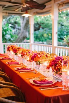 a long table is set up with orange and pink flowers on it for an elegant dinner