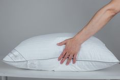 a person's hand reaching for a pillow on a table