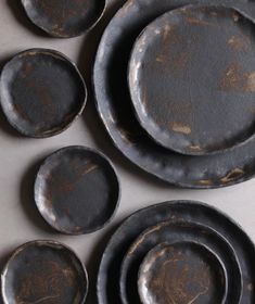 an assortment of black plates and bowls on a white counter top with rusted paint