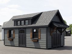 a small gray building with two windows on the roof