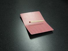 a red and white square with a matchstick sticking out of it on a black surface