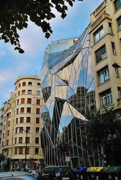 an unusual building in the middle of a city with many cars parked on the street