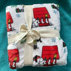 a blanket wrapped in white and red with snoopy dogs on it, next to a blue towel