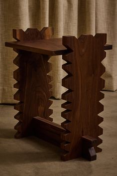 a wooden table sitting on top of a floor next to a window covered in curtains