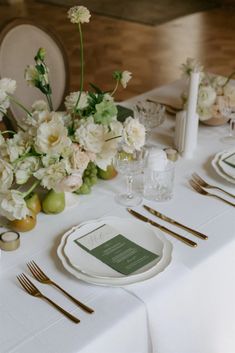 the table is set with white flowers and silverware