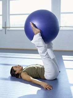 a woman laying on the floor with a large blue ball in front of her head