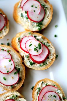 small sandwiches with sliced radishes and cheese on them sitting on a white plate