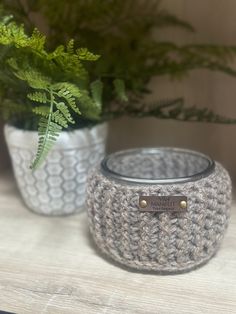 two crocheted pots sitting on top of a table next to a potted plant