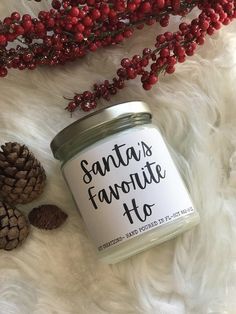 a jar of santa's favorite to candle next to some pine cones and berries