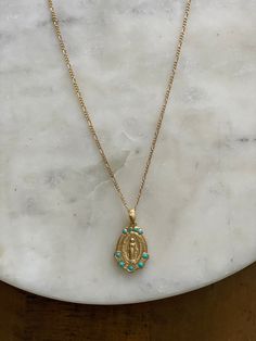 This stunning Miraculous Medal necklace is sure to become a cherished heirloom for years to come! The front of the medal features the image of the traditional Miraculous Mary, wreathed with tiny enamel turquoise accents. On the back, the traditional Miraculous Medal backing is stamped. This necklace was lovingly created using a vintage mold found in a New England jewelry shop. We just adore its timeless and truly classic look! 3/4" medallion, 18"-20" fine cable chain, 14k gold over brass. Design Turquoise Necklace With Vintage Charm As Gift, Turquoise Necklace With Vintage Charm For Gift, Blue Medallion Locket Necklace, Miraculous Medal Medallion Necklace, Turquoise Necklaces With Coin Pendant Medallion, Blue Medallion Necklace With Coin Pendant, Turquoise Amulet Necklace With Charms, Turquoise Medallion Locket Jewelry, Spiritual Turquoise Medallion Necklace