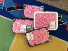 three packages of pink yarn sitting on top of a rug