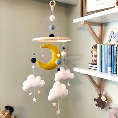 a baby crib mobile with clouds, stars and the moon hanging from it's side