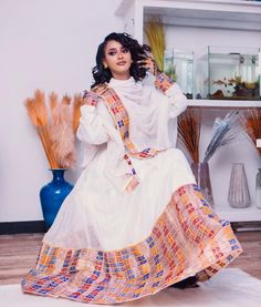 This radiant Habesha Kemis is a true masterpiece of Ethiopian fashion. The dress features a stunning Tilf design that is intricately woven into the fabric, creating a beautiful and unique pattern that catches the eye. The Tilf design is complemented by the Tilet bottom of the dress, which adds a touch of elegance and sophistication to the overall look. The Habesha Kemis is made from high-quality fabric that is soft to the touch and drapes beautifully on the body. The dress is designed to flatter Ethiopian Fashion, Eritrean Dress, Ethiopian Clothing, Habesha Dress, Ethiopian Traditional Dress, Ethiopian Dress, Habesha Kemis, Traditional Weaving, Traditional Clothes