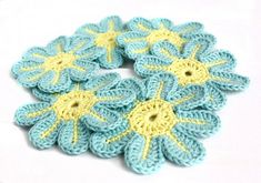 four crocheted blue and yellow flowers on a white surface