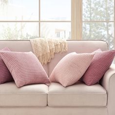 a couch with pink pillows in front of a window