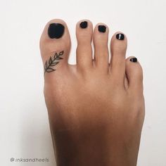 a woman's foot with black nail polish and leaves on the tip of her toe