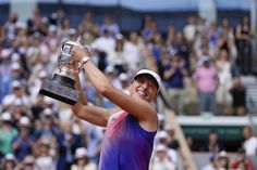 a tennis player holding up a trophy in front of a crowd