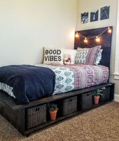 a bed with baskets underneath it and lights on the wall above it, in a room with carpeted flooring