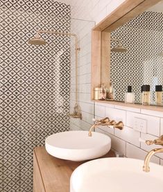 two white sinks sitting under a mirror in a bathroom next to a wooden counter top