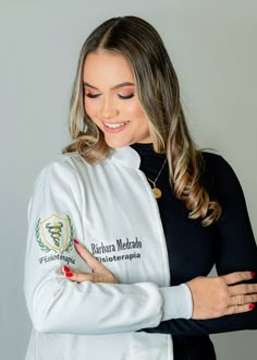 a woman wearing a white and black jacket with her arms crossed, smiling at the camera