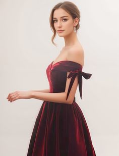 a woman in a red dress with a bow on her shoulder, posing for the camera