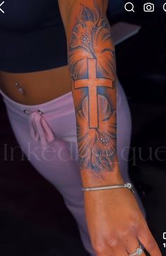 a woman's arm with a cross tattoo on it and flowers in the middle