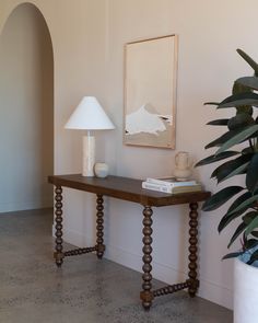 a wooden table sitting next to a plant and a lamp on top of a hard wood floor