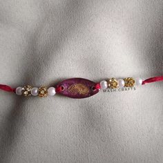 a beaded bracelet with red cord and white beads on the end is decorated with gold accents