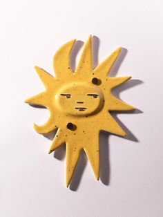 a yellow sun with black dots on it's face is shown against a white background