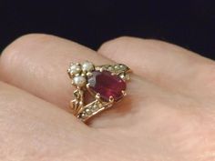 "A royal arrangement of garnet and seed pearls on this elegant Victorian ring.Three seed pearls crown the .40 oval faceted garnet.Two diagonal shoulder pieces with four inset seed pearls complement this gorgeous setting.Shorter, gold plumed braces balance out the design.Eight prongs hold the garnet and thirteen prongs hold the three pearls in place. Inside the ring band is inscribed,\"G. to A.\" in Victorian script. What a romance this must have been! Ring size: 7 US, N 1/2 UK, 14 Japan, China, Pearls Ring, Wedding Band Engraving, Victorian Ring, Unusual Rings, Art Deco Diamond Rings, Engraved Wedding, Star Ring, Art Deco Diamond, Seed Pearl