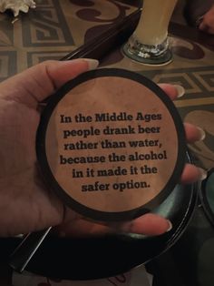 a person holding up a coaster that says in the middle age people drink beer rather than water