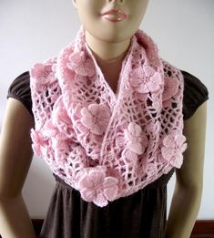 a woman wearing a pink crocheted scarf on top of a mannequin